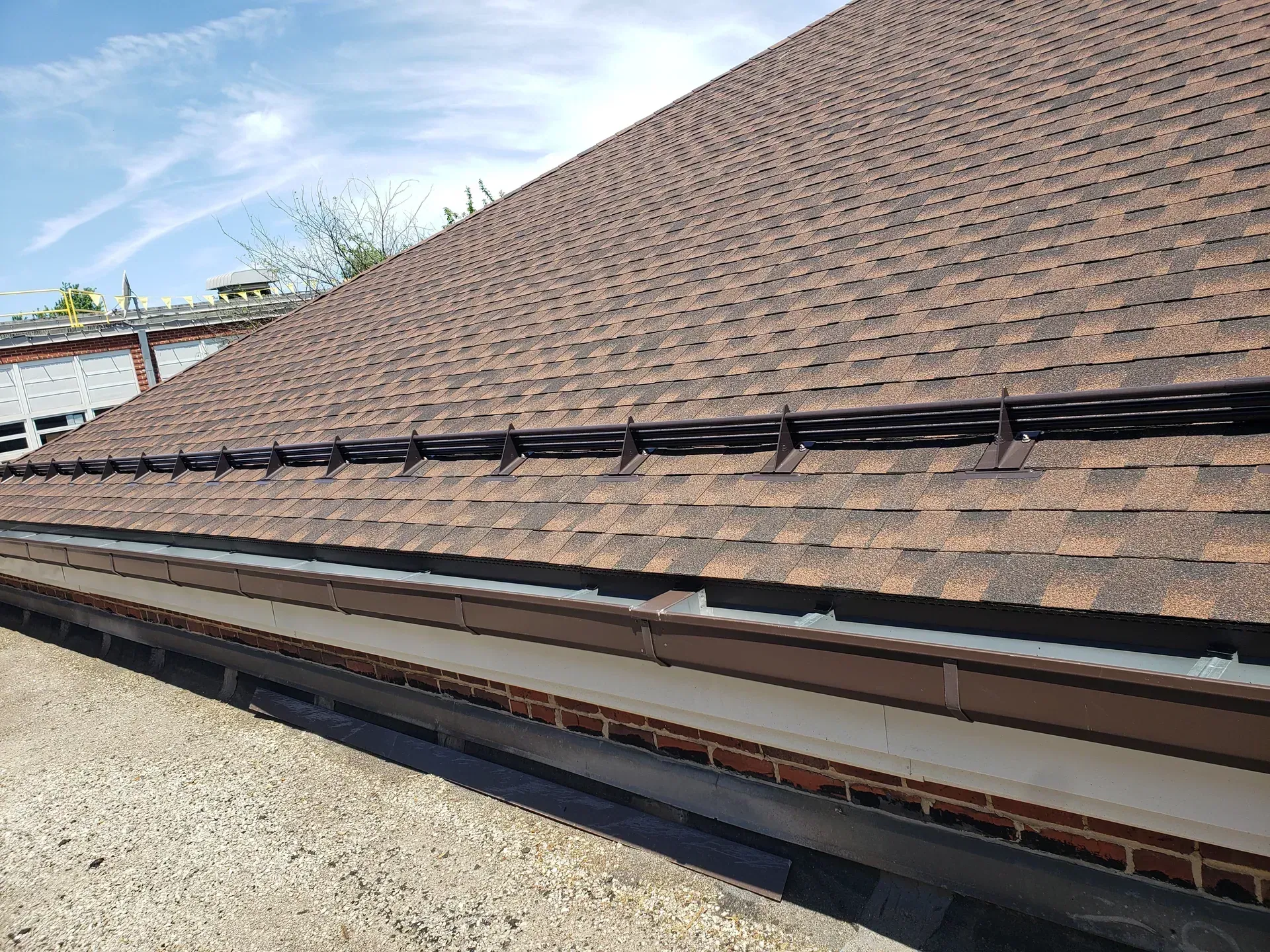 Finished brown architectural shingle roof with snow guards and a new gutter